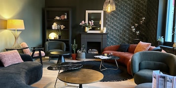 Uma sala de estar moderna com sofá, poltronas, mesa de centro, lareira e objetos decorativos.