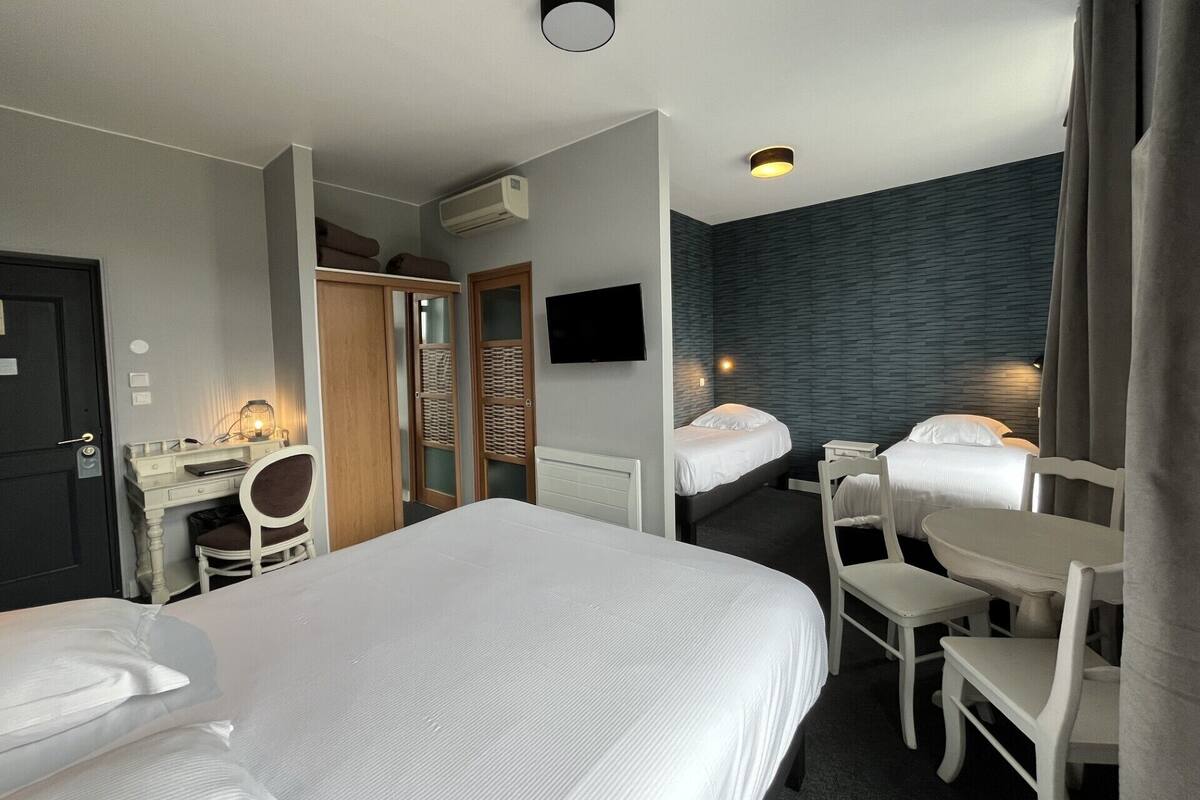 A hotel room with two beds, a desk, a chair, a TV, and a wardrobe.