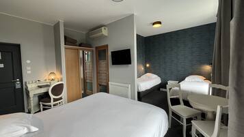 Una camera d'albergo con due letti, una scrivania, una sedia, una TV e un armadio.
