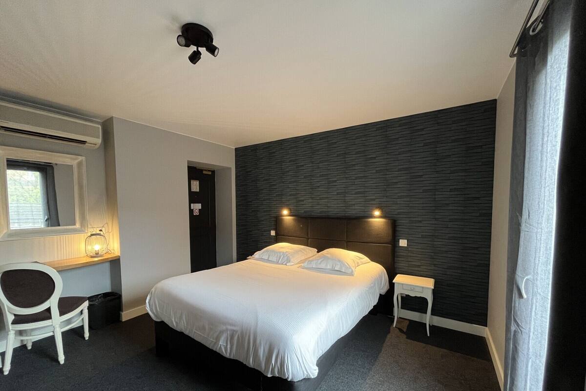 A modern hotel room with a large bed, a desk, and a chair.