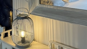 A hotel room with a bed, a nightstand, a lamp, and a mirror reflecting the bed. - Hôtel Saint Jean (Wimereux)