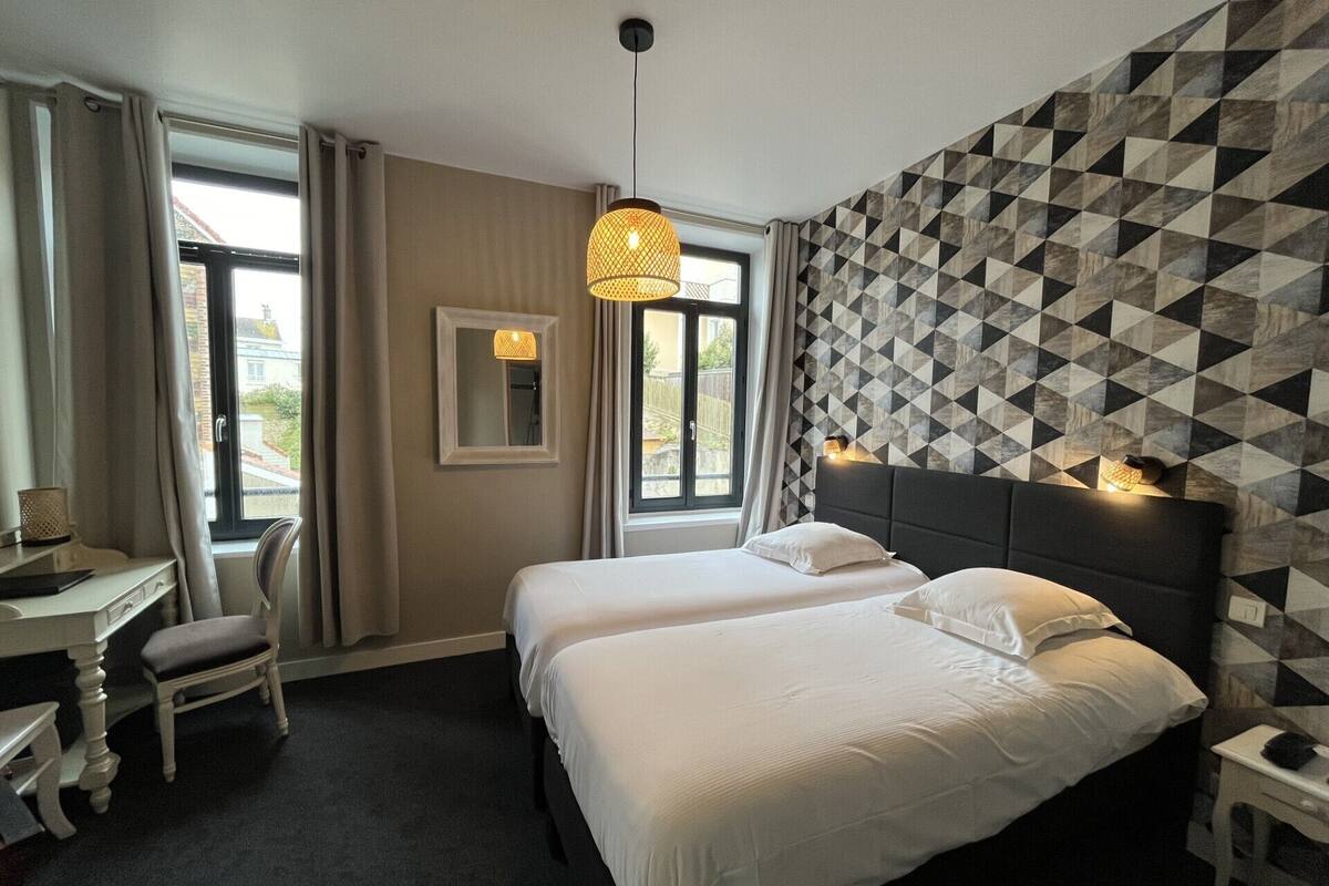 A hotel room with two beds, a desk, a chair, and a large window.