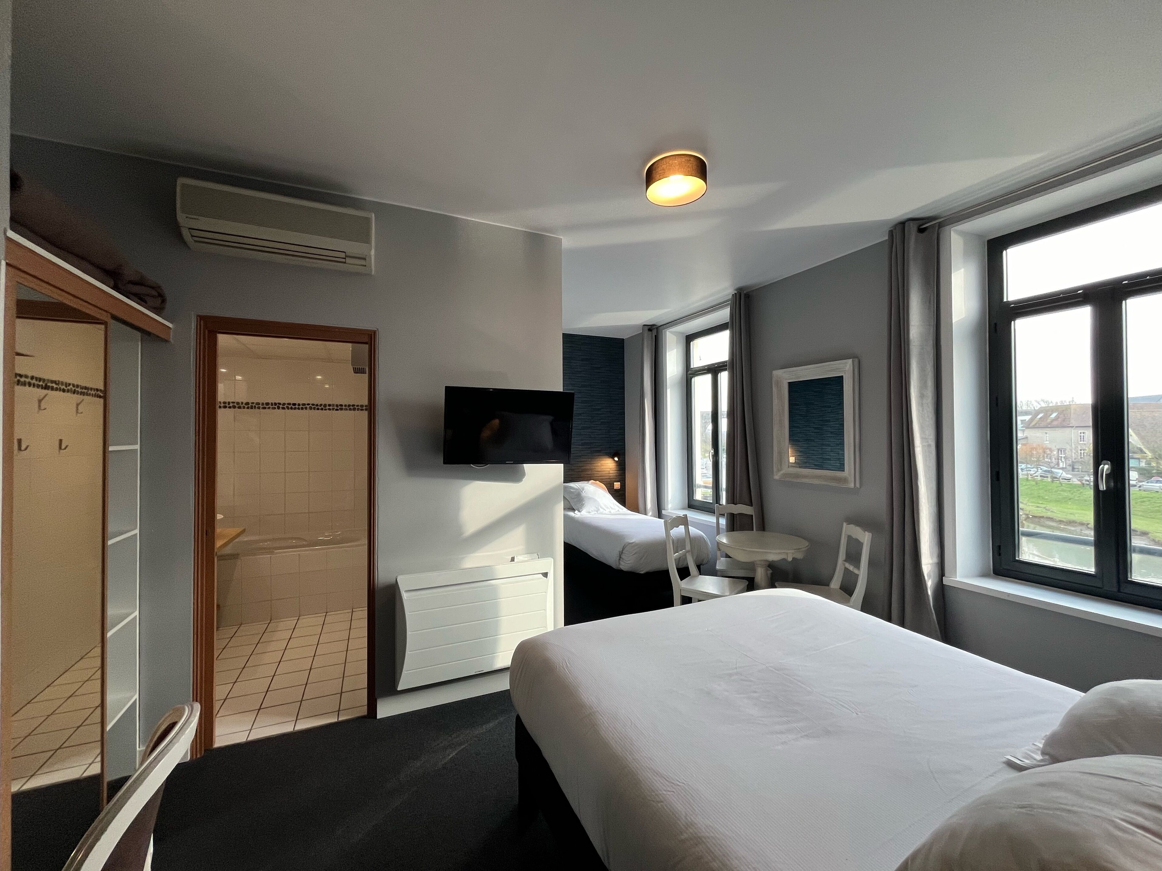 Una camera d'albergo con un letto, una TV, una finestra vista, una scrivania e una sedia.