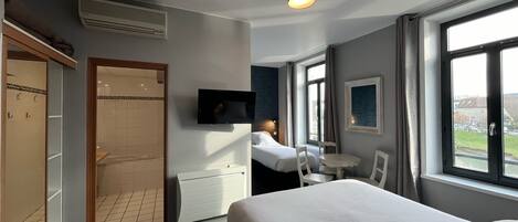 Una camera d'albergo con un letto, una TV, una finestra vista, una scrivania e una sedia.