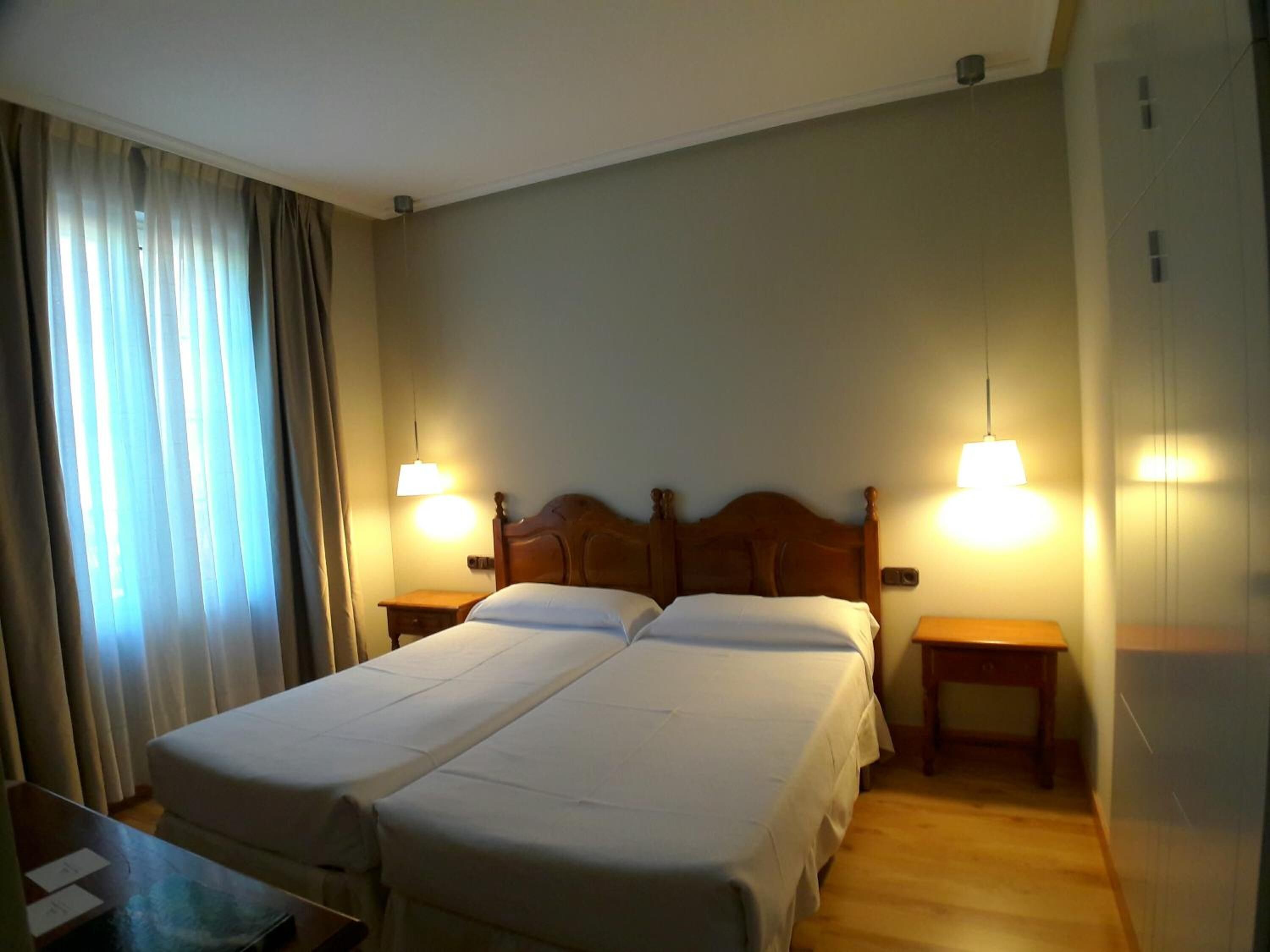 A double bed with a wooden headboard, two bedside tables, and a desk with a chair.