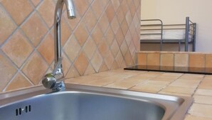 A kitchen with a stainless steel sink, tiled backsplash, and a metal bench. - B&B Rainbow (Naples)