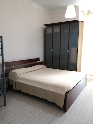 A bedroom with a bed, a wardrobe, and a ladder.