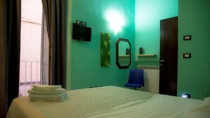 A hotel room with a bed, a chair, a TV, and a door. - B&B Rainbow (Naples)