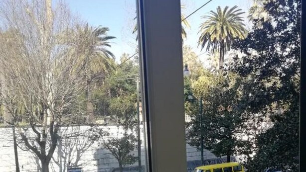 A view from a window overlooking a street with vehicles, including a yellow van and a white car, and trees in the background. - B&B Rainbow (Naples)