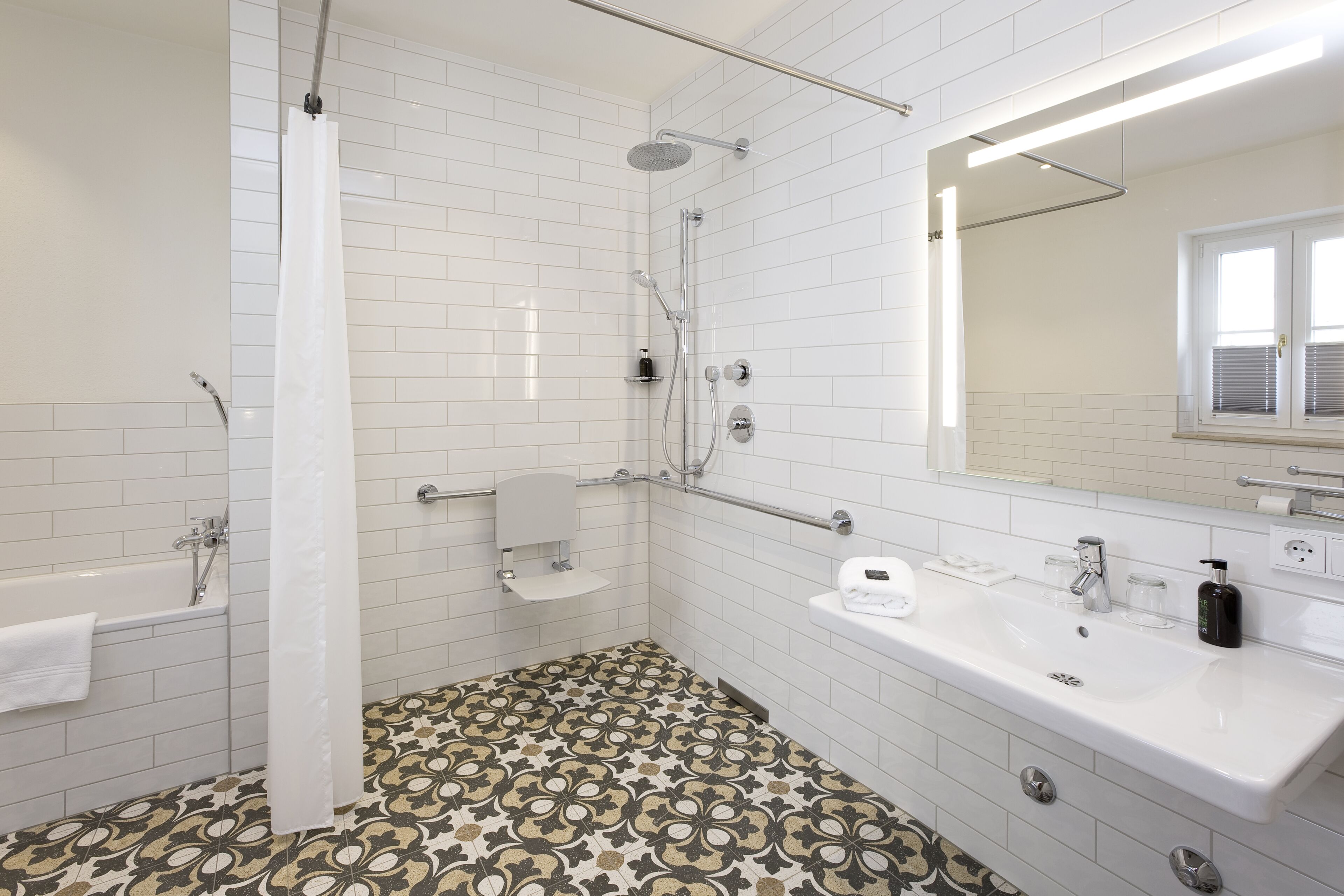 A modern bathroom with white tiles, a shower, a bathtub, a sink, and a mirror.