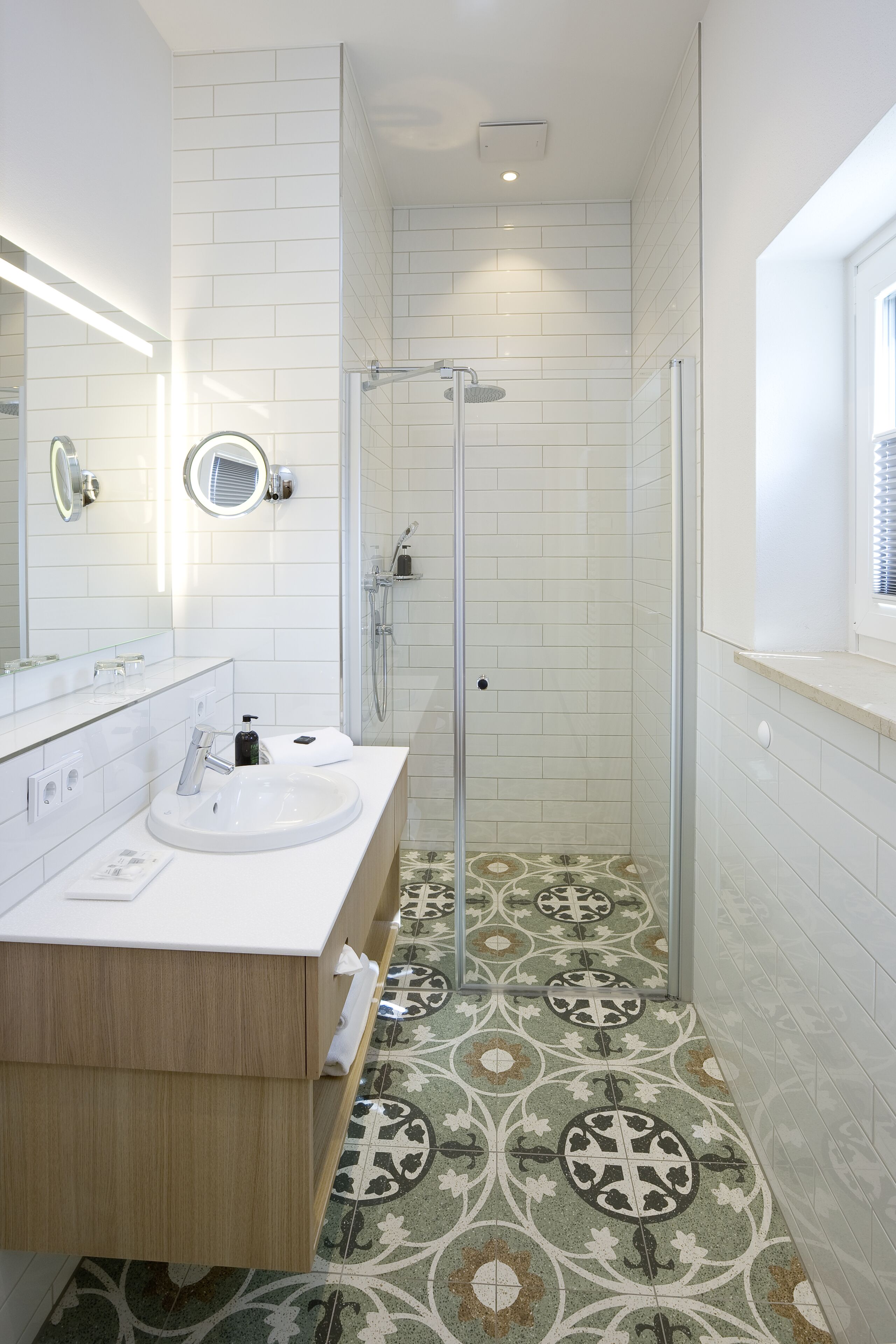 Ein modernes Badezimmer mit zwei Waschbecken, einer gläsernen Dusche und Fliesen mit Muster.