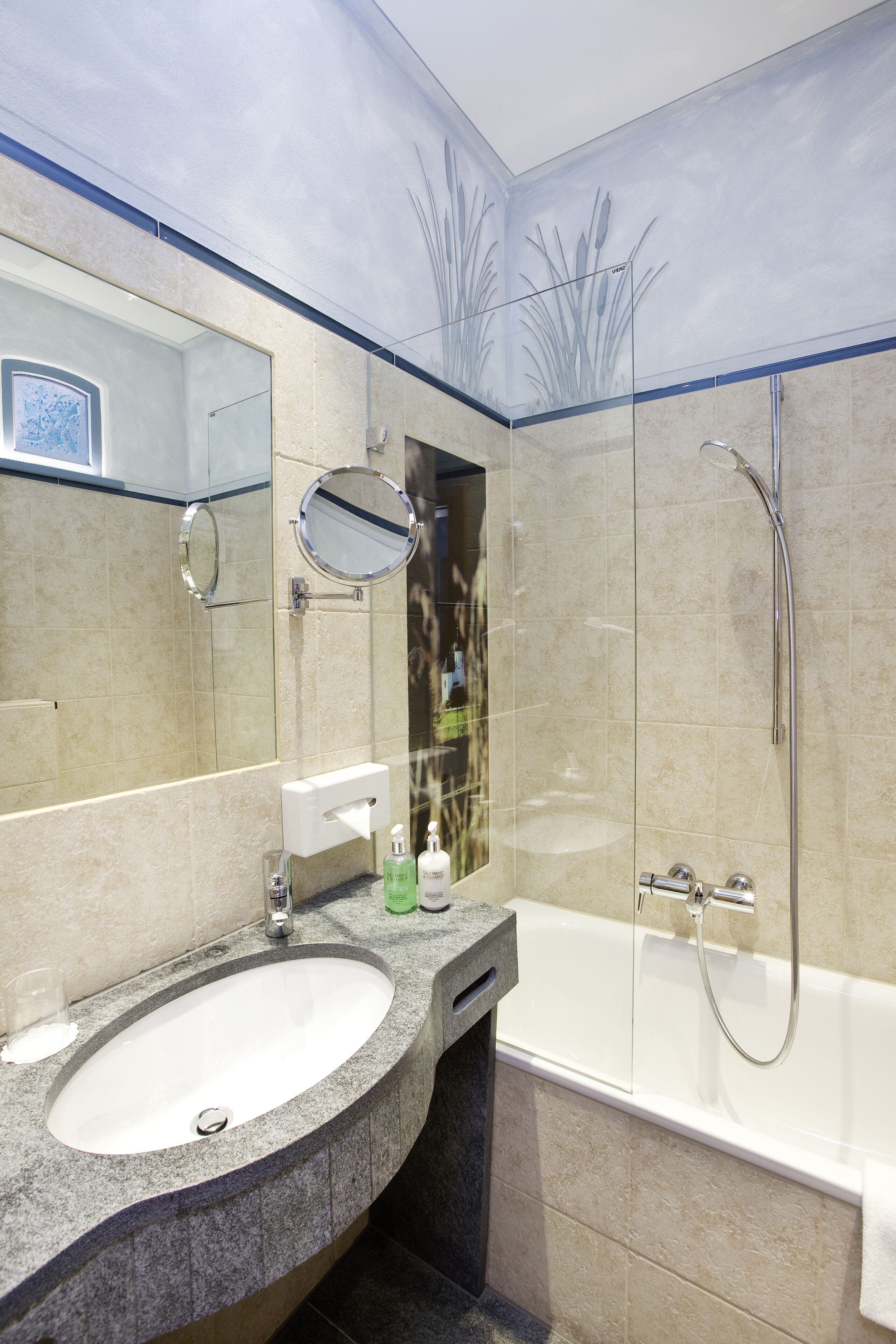 Ein modernes Badezimmer mit einem Granittischwaschbecken, einem Spiegel, einer Handbrause und einer Badewanne.