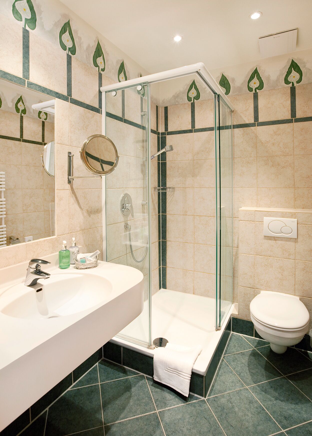 Un baño moderno con ducha de vidrio, un lavamanos grande con espejo y un inodoro.