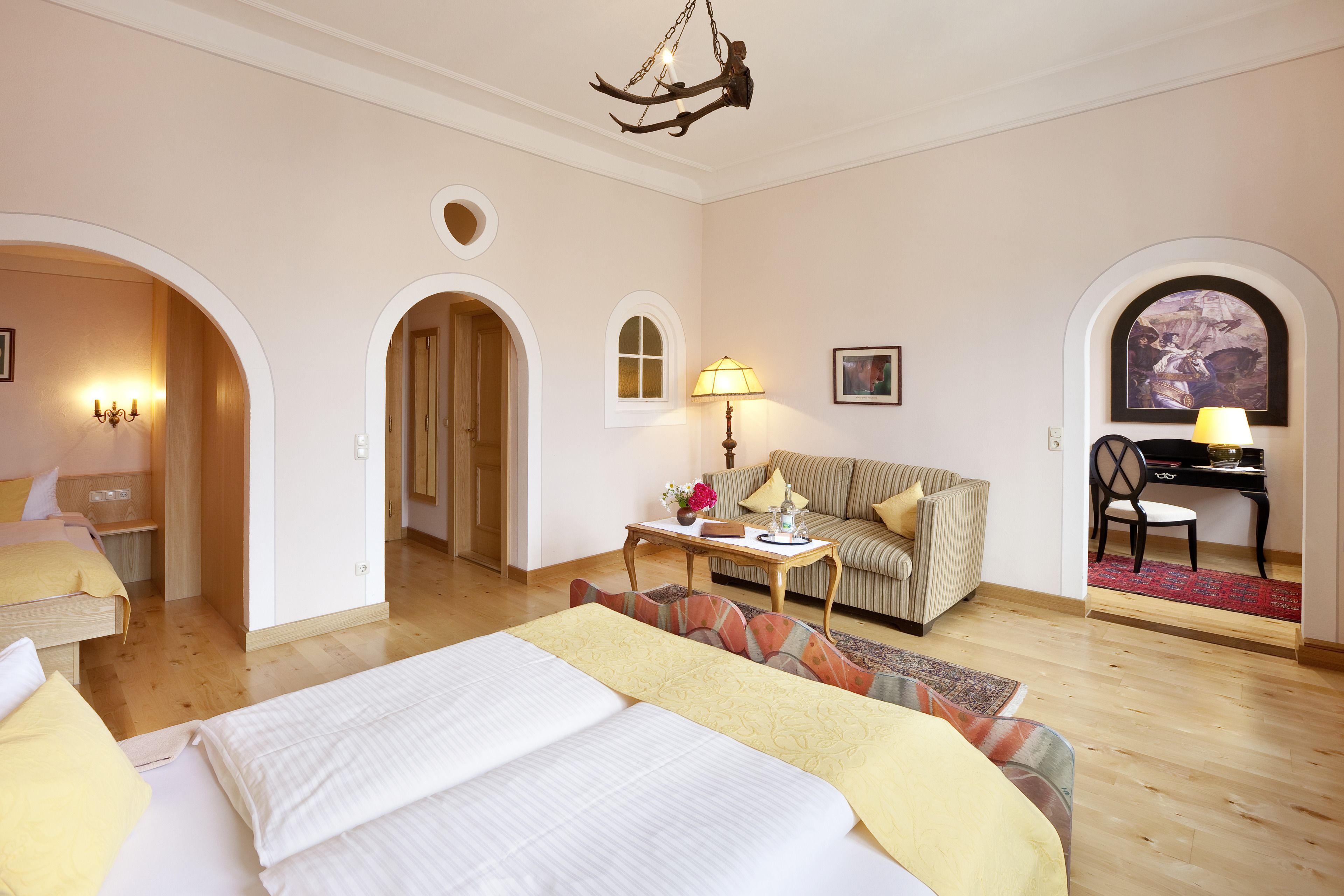 Quarto de hotel com uma cama grande, um sofá, uma escrivaninha com cadeira e um espaço de refeições com um piano.