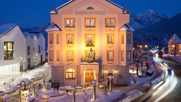 Een groot, goed verlicht hotelgebouw met een opvallende ingang en een kerstboom ervoor.