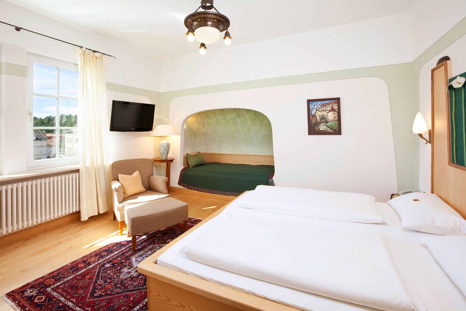 Een hotelkamer met een groot bed, een stoel, een televisie en een raam met gordijnen.