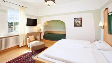 Een hotelkamer met een groot bed, een stoel, een televisie en een raam met gordijnen.
