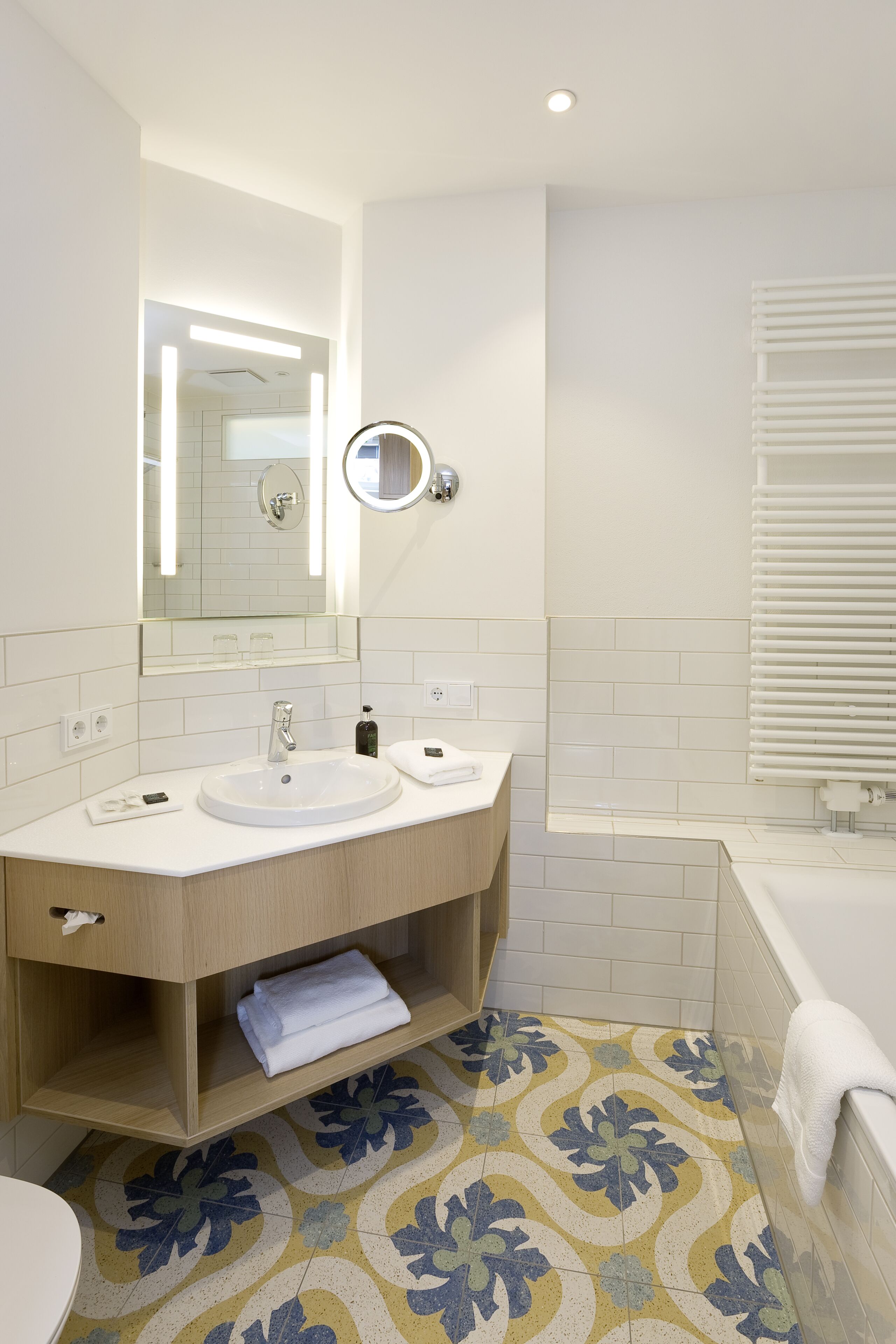 Een moderne badkamer met twee wasbakken, een spiegel en een bad.