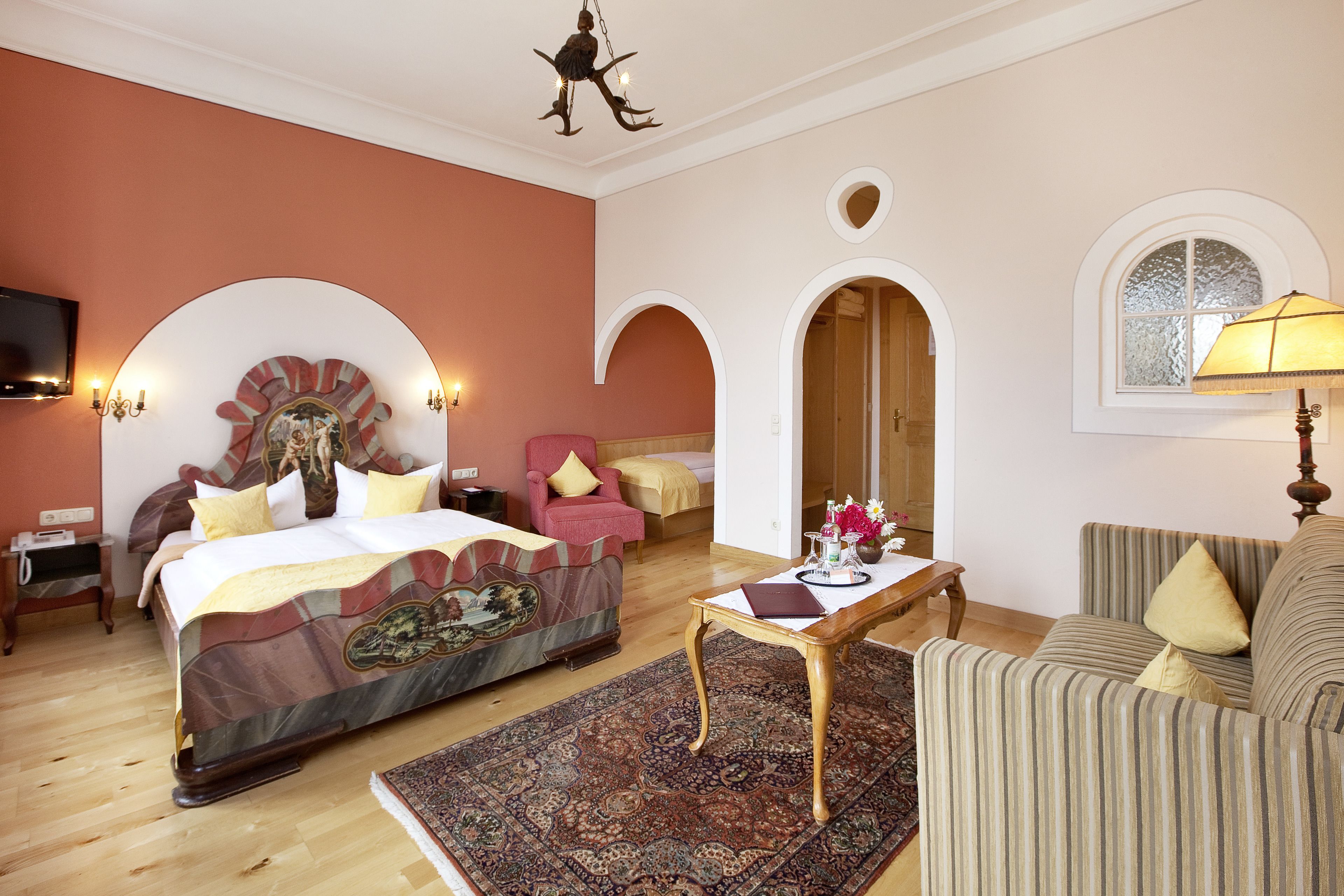 A bedroom with a large bed, a sofa, a coffee table, and a TV.