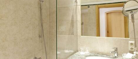 A modern bathroom with a glass-enclosed shower, a freestanding bathtub, and a marble sink.