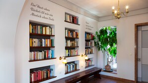 Een bibliotheek met boekenkasten, een bank en een kroonluchter.
