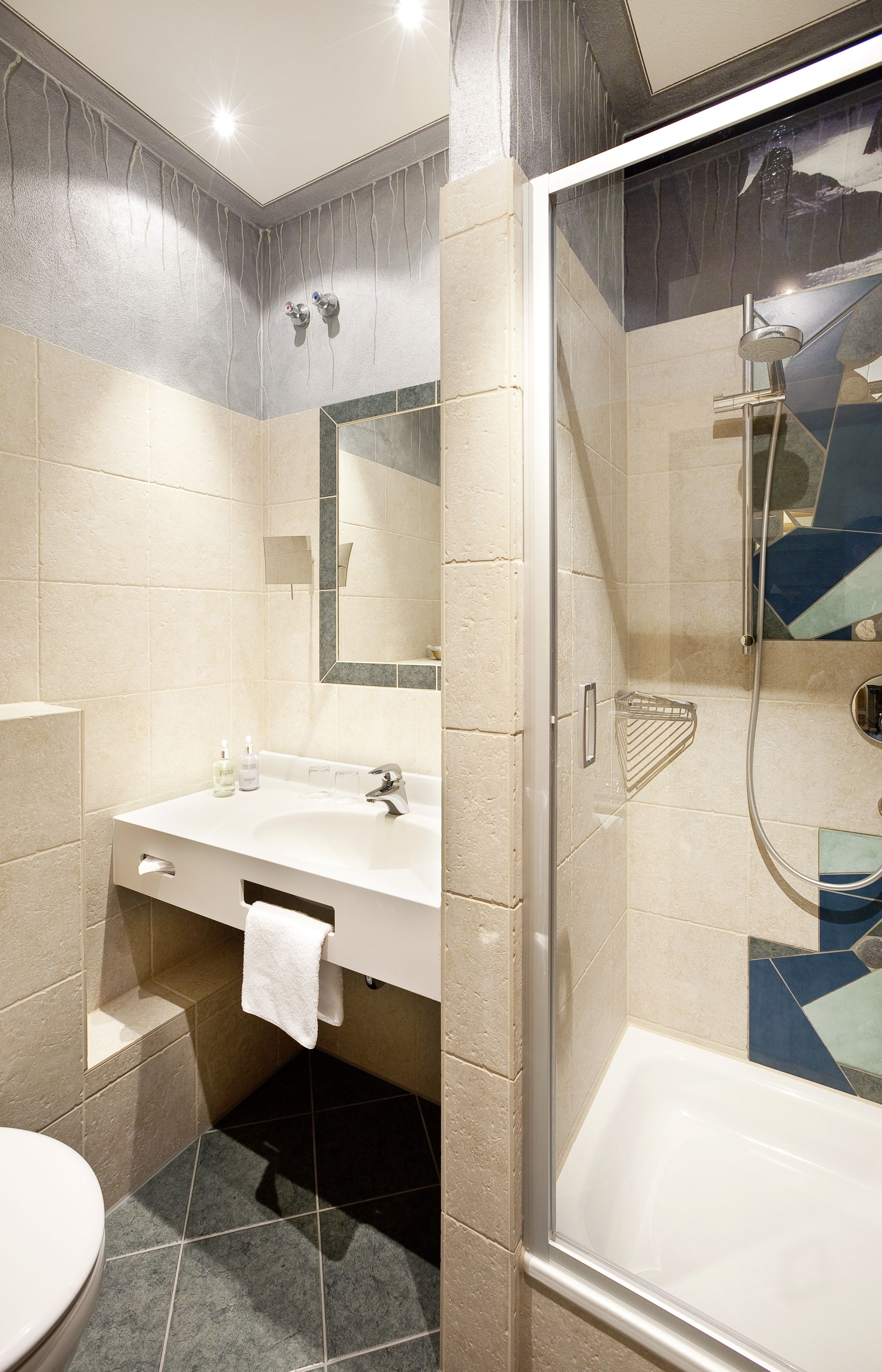 Een moderne badkamer met een douche, wastafel en toilet.