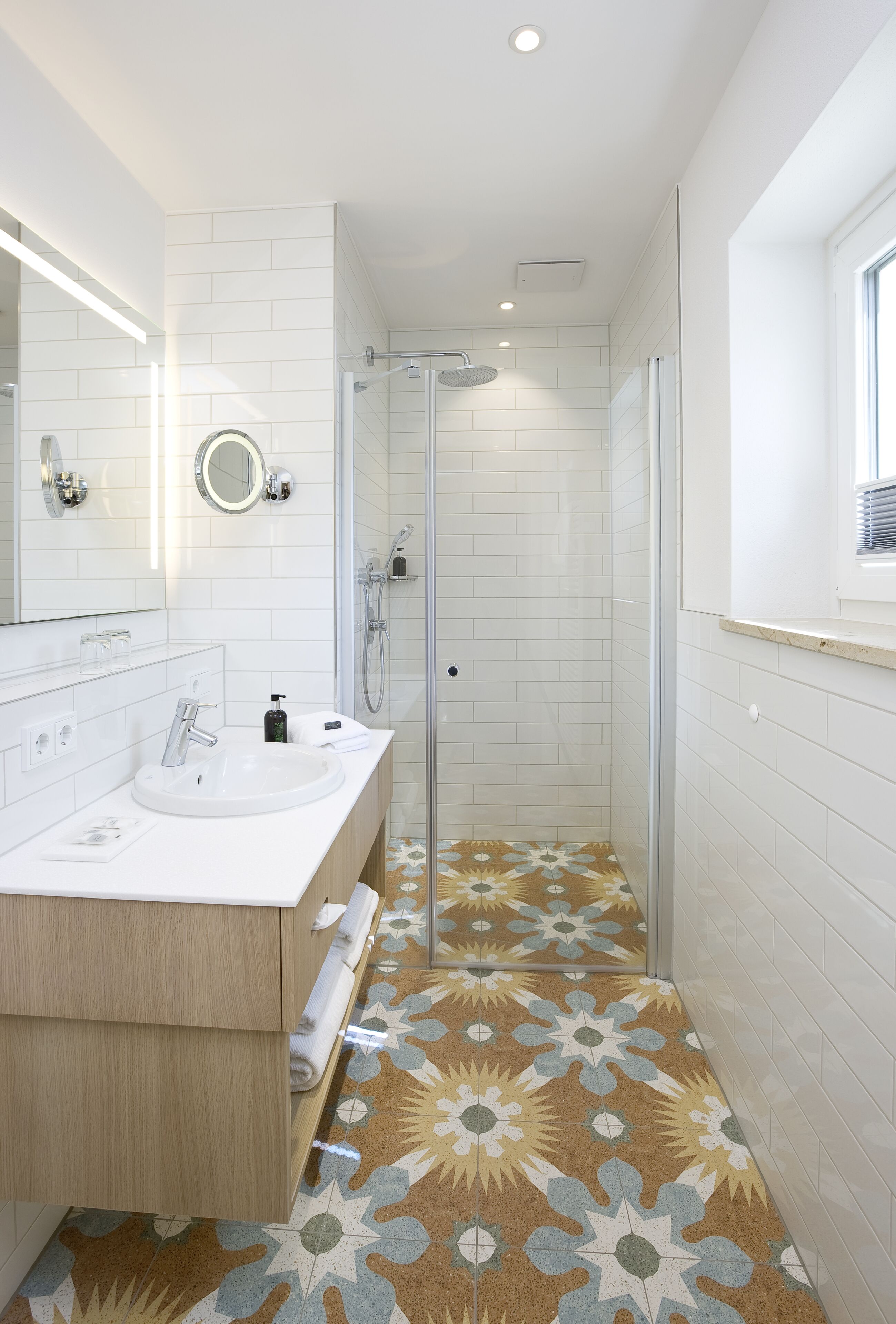 Een moderne badkamer met een witte wastafel, spiegel en douche.