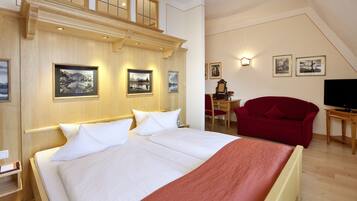 Ein Hotelzimmer mit einem großen Bett, einem roten Sessel, einem Schreibtisch mit Stuhl und einem Fernseher.