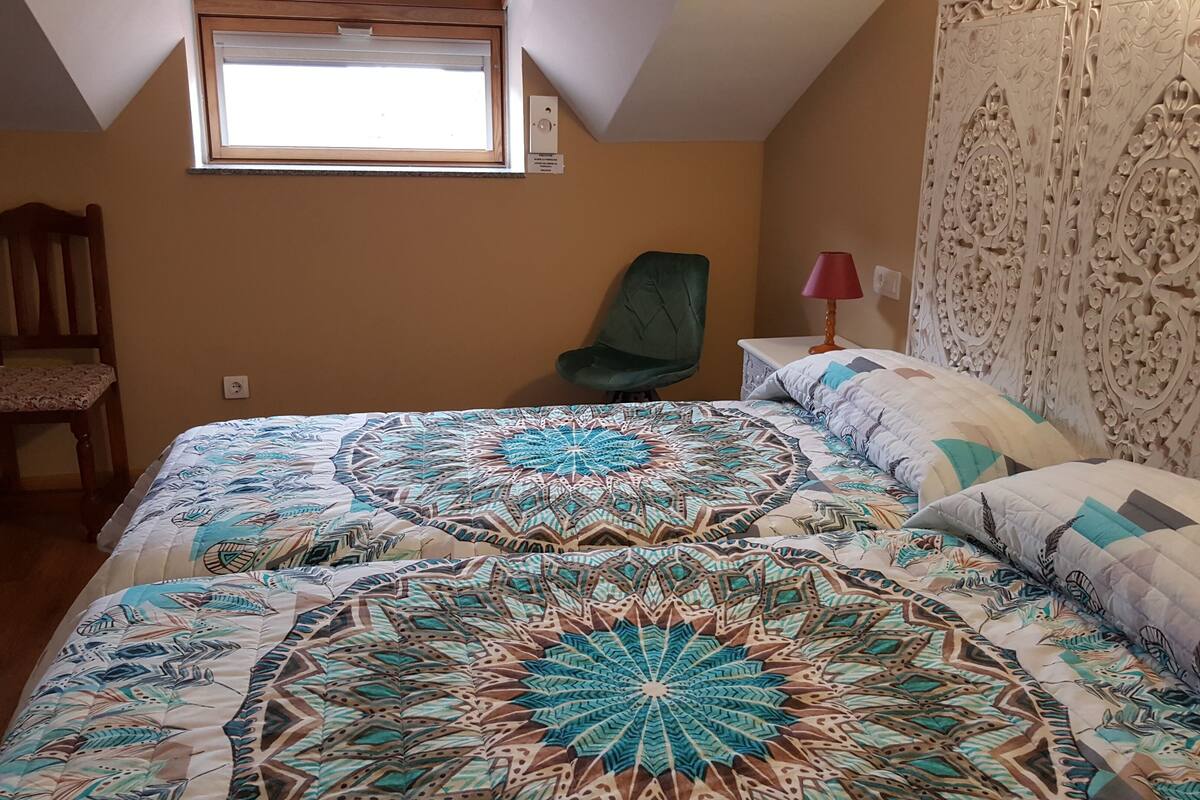 A bedroom with a large bed, a chair, a window, and a decorative headboard.