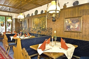 Un restaurante con paneles de madera, asientos tapizados en azul y una araña.