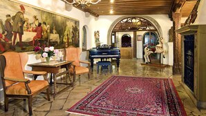 A spacious room with a grand piano, a chandelier, and a large painting on the wall.