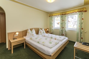Ein Schlafzimmer mit einem Bett, zwei Nachttischen, einem Schreibtisch und einem Fenster mit Vorhängen.