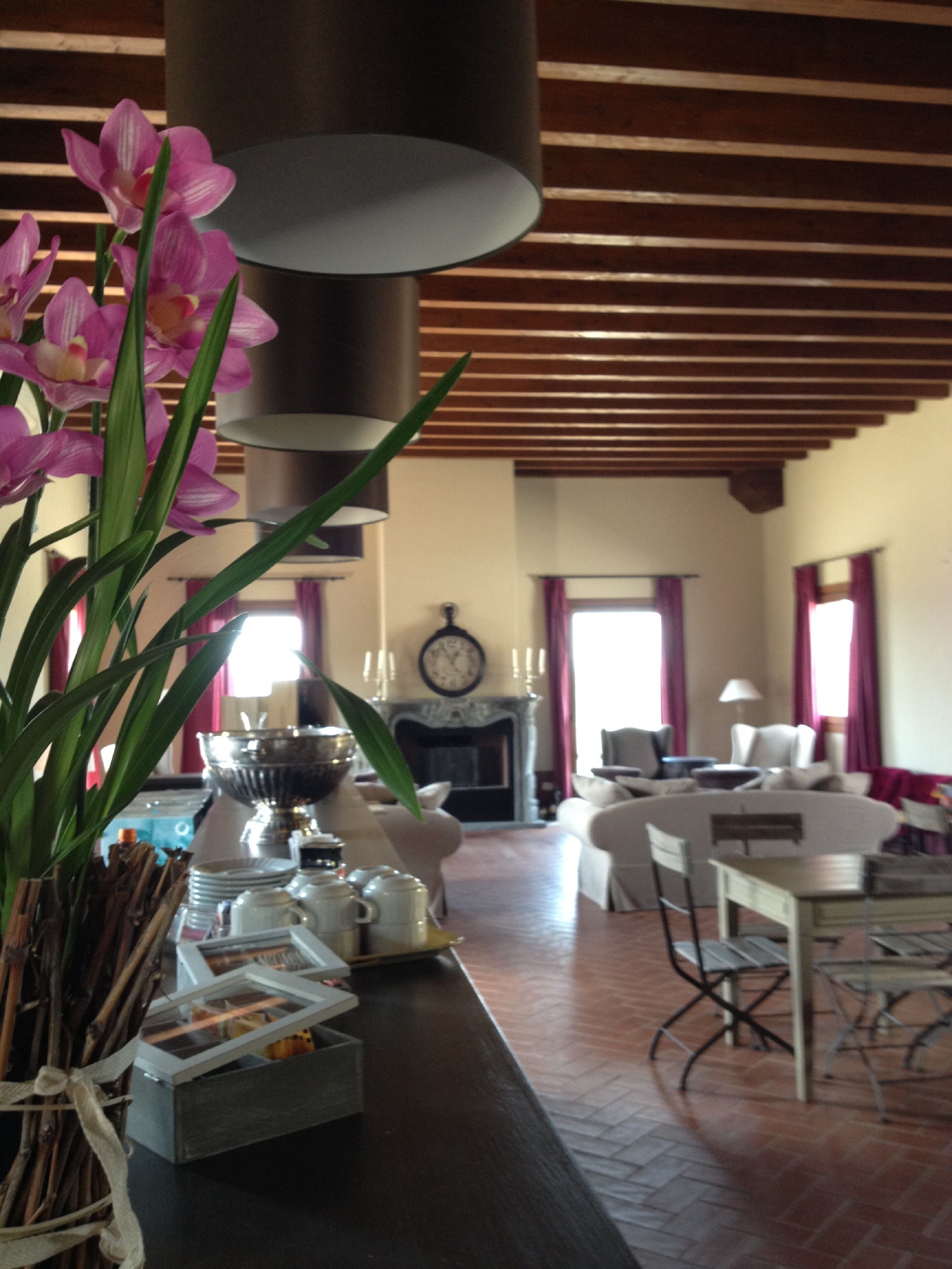 A dining area with a table set for a meal, a vase of flowers, and a fireplace in the background.