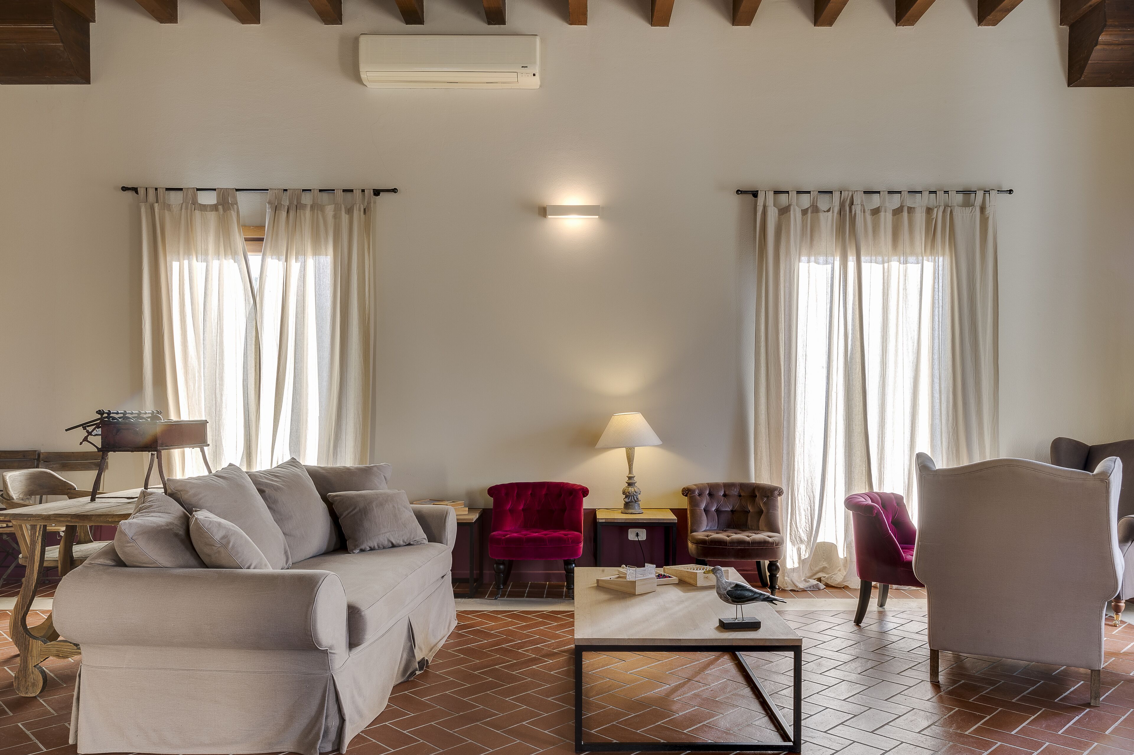 Un salon avec un canapé, des fauteuils, une lampe et une table.