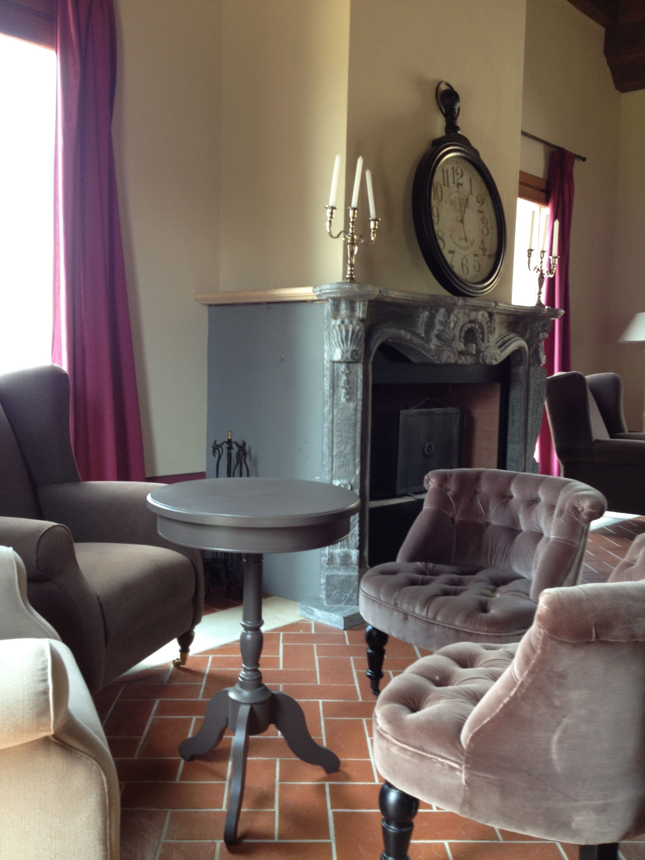 Un salon avec une cheminée, une table ronde et deux fauteuils.