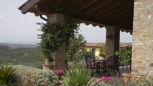 A covered outdoor seating area with stone pillars, a table, and chairs. - Antico Casale L'Impostino (Civitella Paganico)