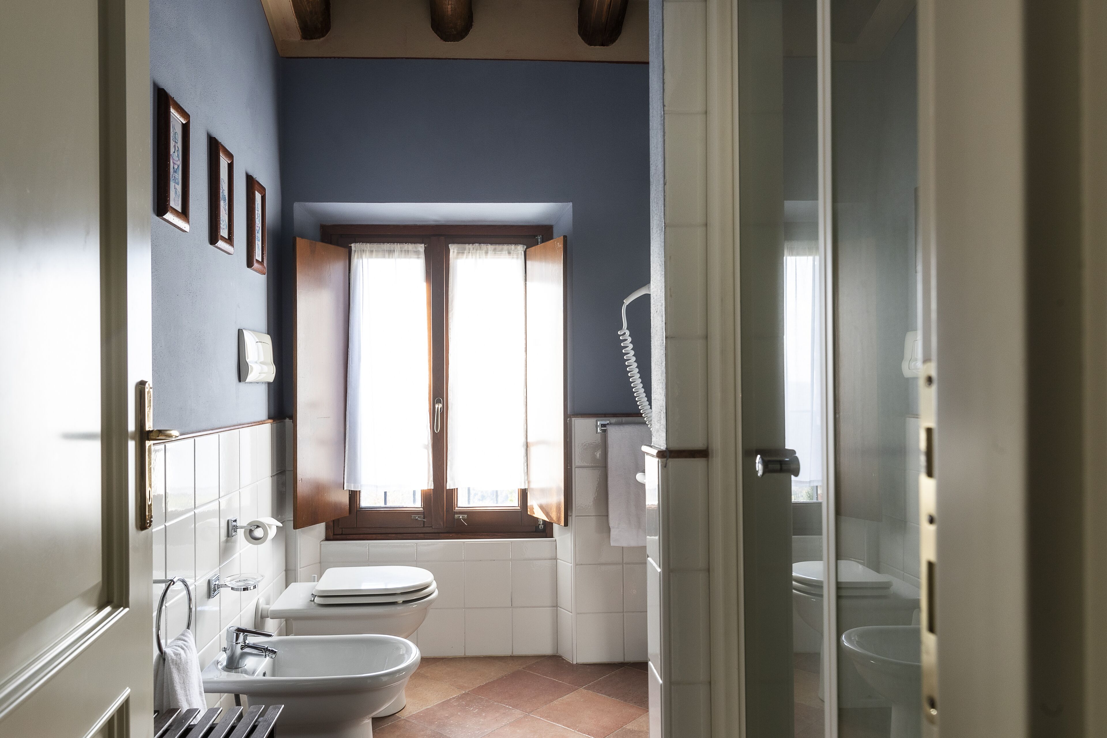 A bathroom with a bathtub, two toilets, a window, and a shower.