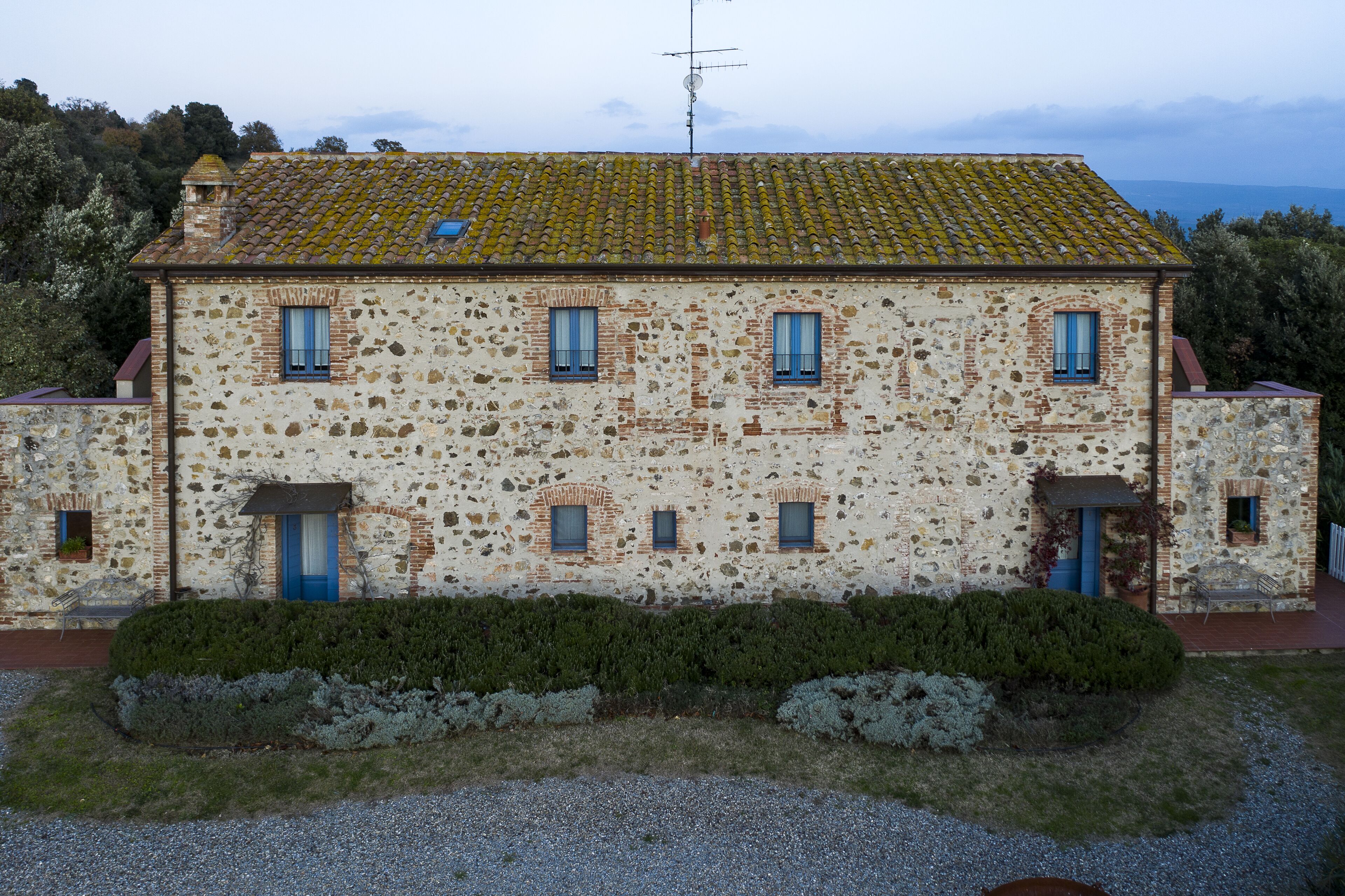 Un edificio de piedra de dos pisos con múltiples ventanas y techo de tejas.