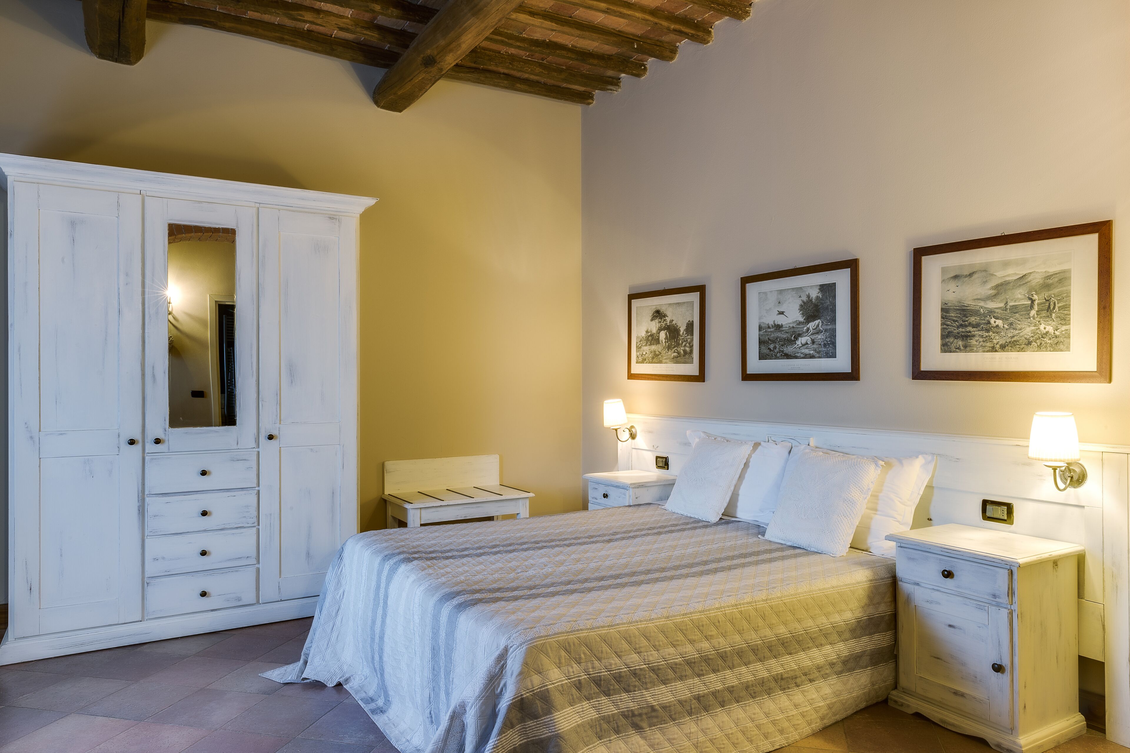 A bedroom with a bed, nightstands, a wardrobe, and wall-mounted lamps.