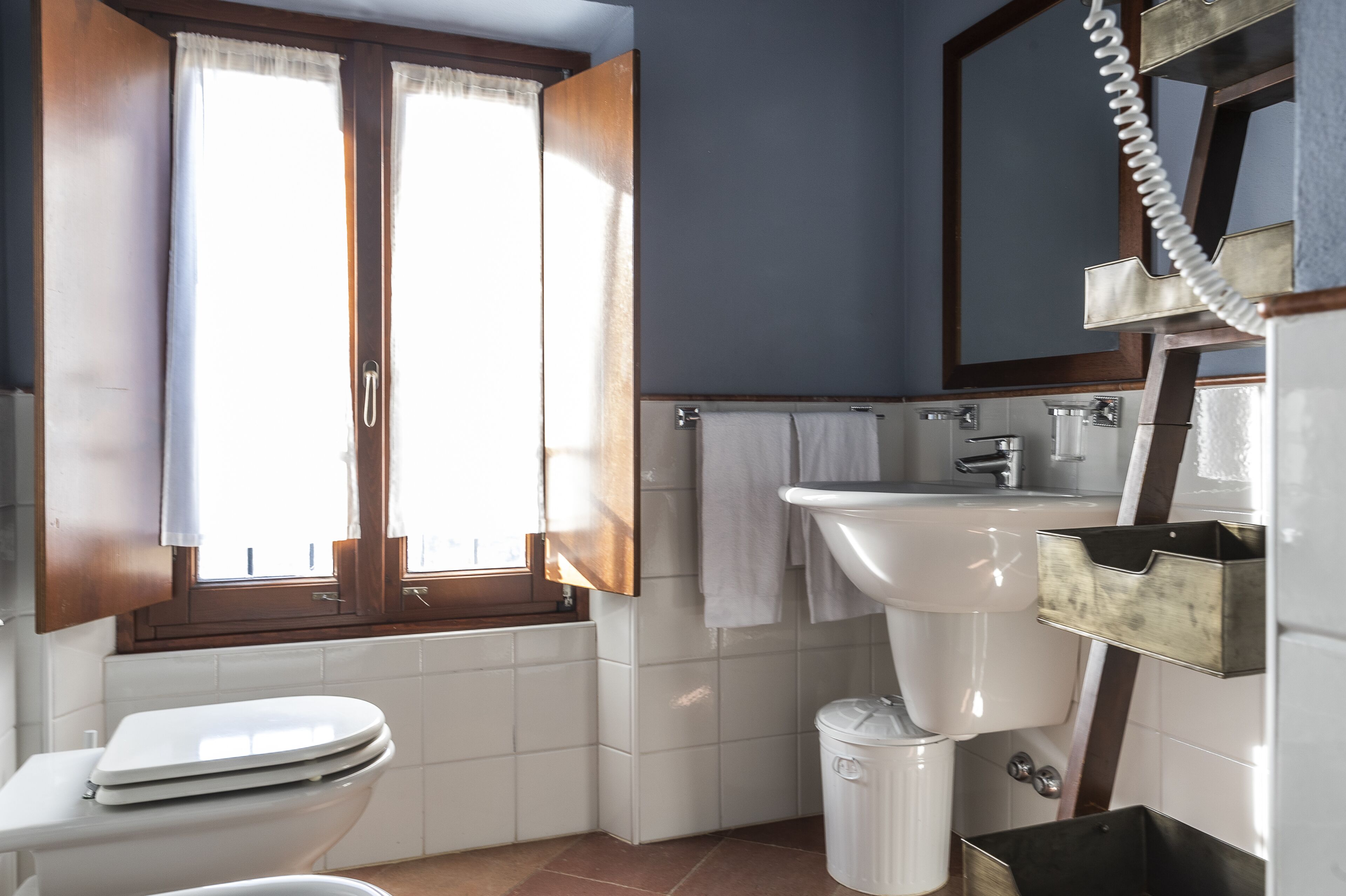 A bathroom with a toilet, sink, and window with curtains.