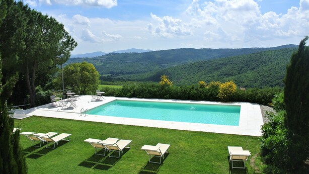 A rectangular swimming pool with a clear blue water, surrounded by a well-maintained lawn and several lounge chairs. - Antico Casale L'Impostino (Civitella Paganico)