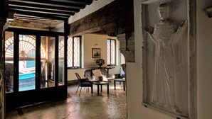 A room with a large window, a table with chairs, and a sculpture on the wall. - Ca' Foscolo Residence (Venice)