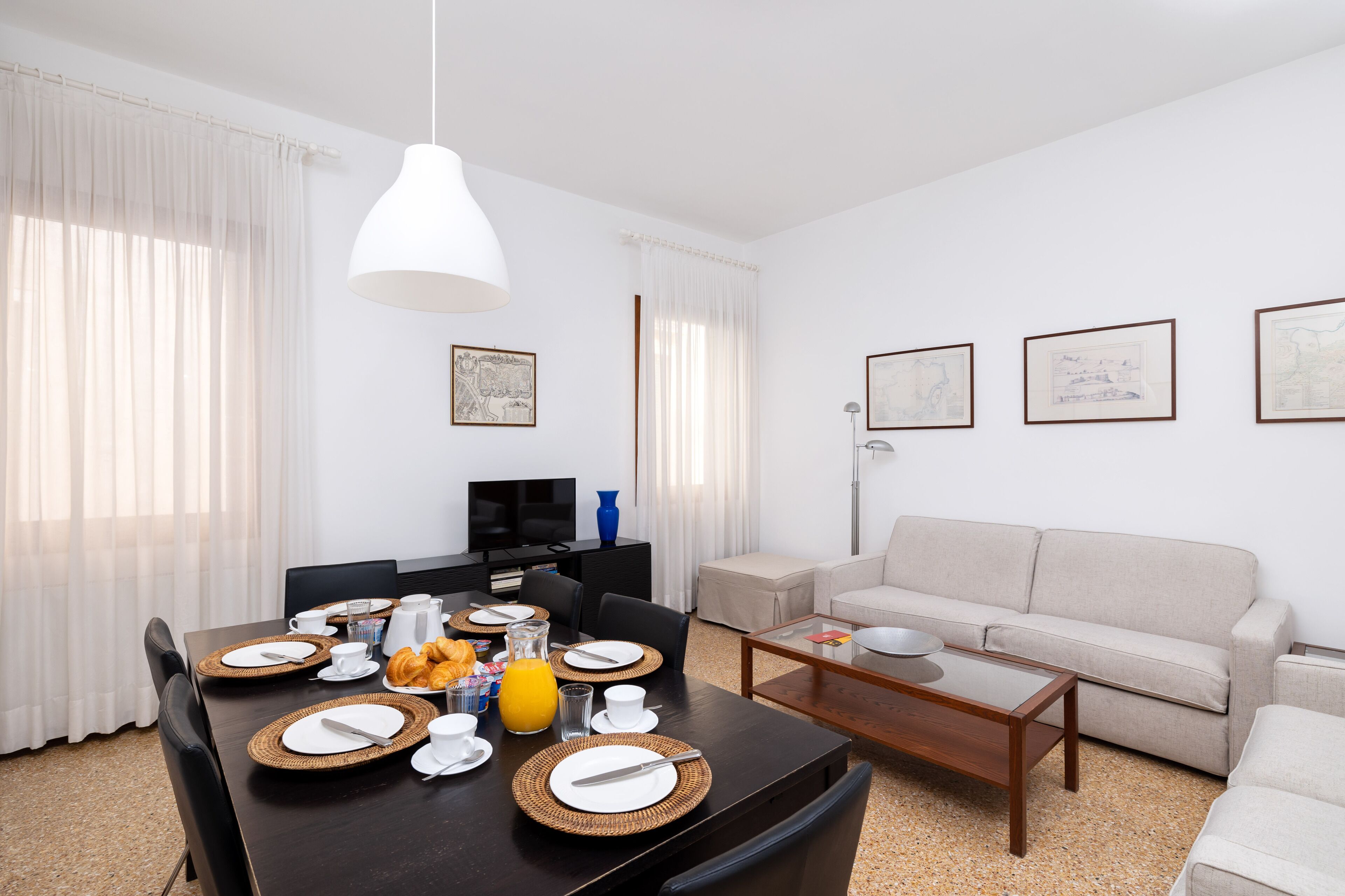 Un salon moderne avec un coin repas, aménagé avec un canapé, une table basse et une table à manger préparée pour le petit-déjeuner.