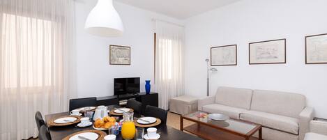 Un salon moderne avec un coin repas, aménagé avec un canapé, une table basse et une table à manger préparée pour le petit-déjeuner.