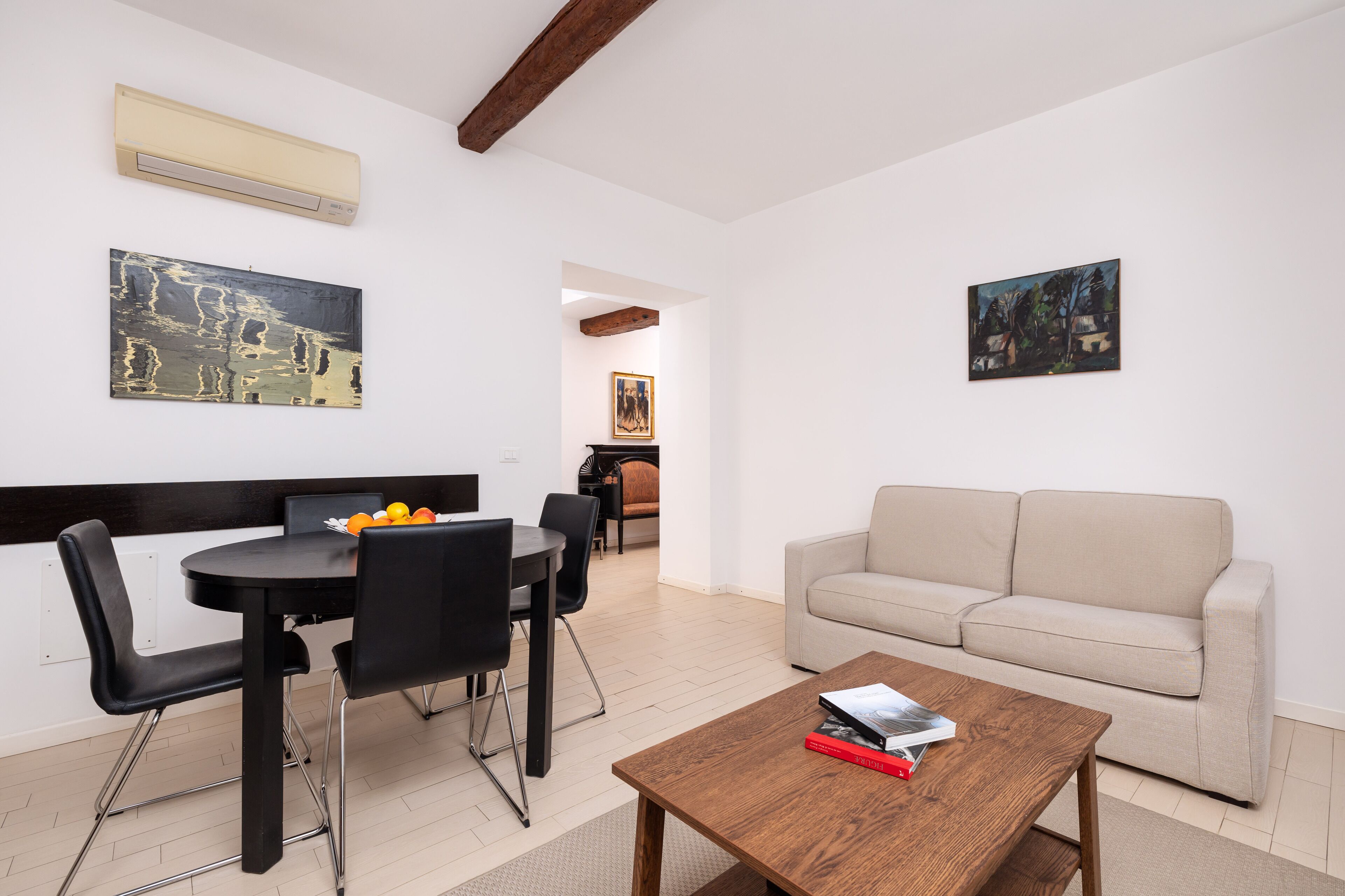 Una sala de estar moderna con comedor, un sofá y dos cuadros en las paredes.