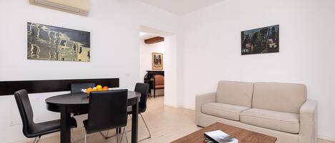 Una sala de estar moderna con comedor, un sofá y dos cuadros en las paredes.