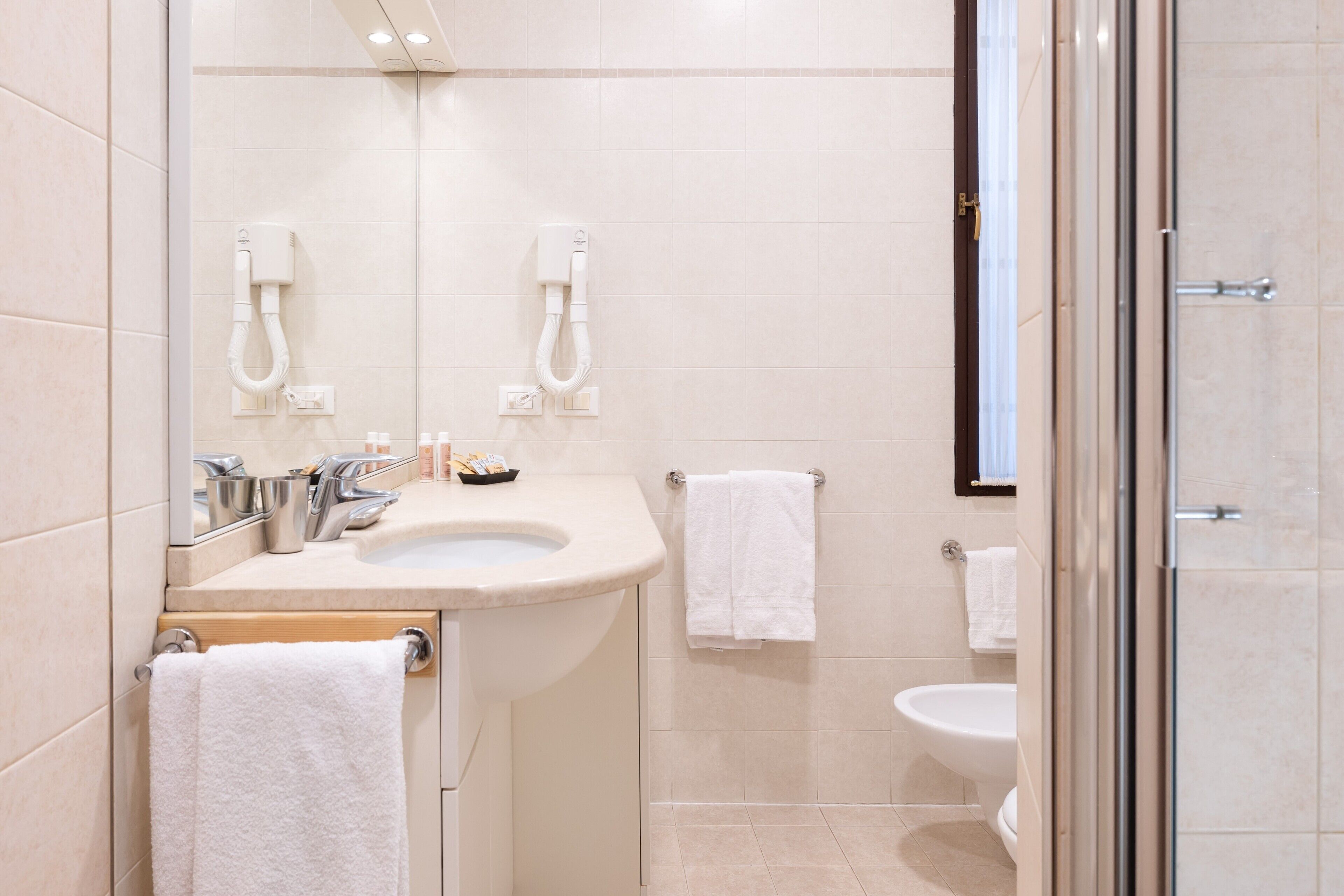 A modern bathroom with a sink, mirror, and two towel racks.