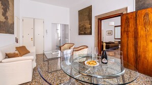 A modern living room with a glass table, a sofa, and a wooden accent wall. - Ca' Foscolo Residence (Venice)
