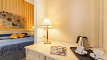 Una camera d'albergo con un letto, una scrivania con una lampada, una macchina del caffè e una rivista sul vassoio.