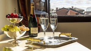 A table with a champagne bottle, glasses, and a fruit bowl. - Hotel Bella Venezia (Venice)